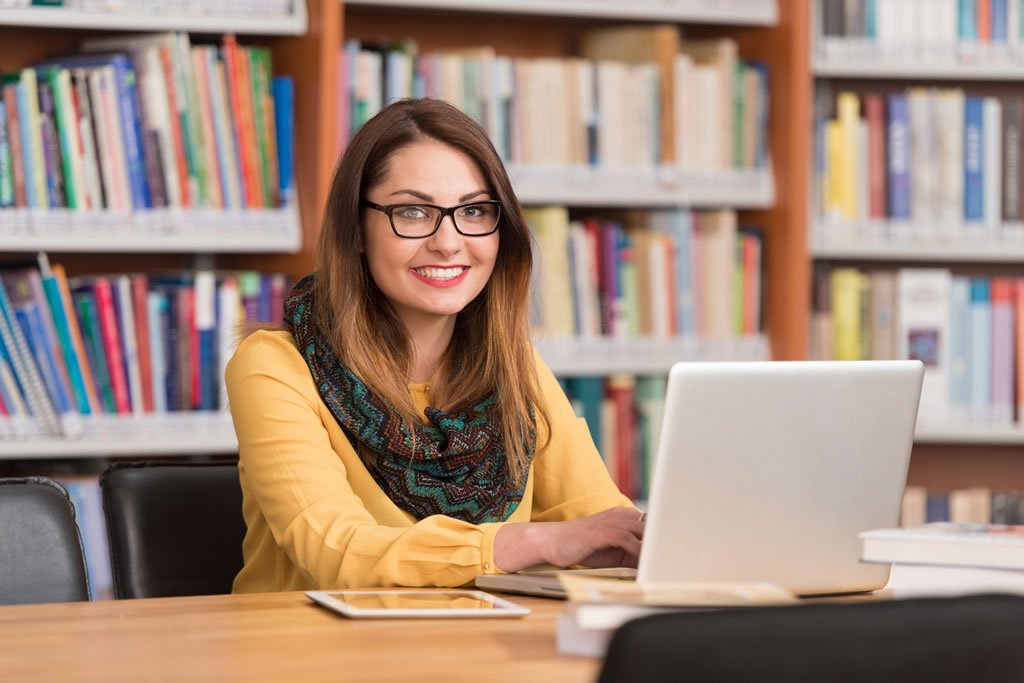 Teacher in library working on laptop